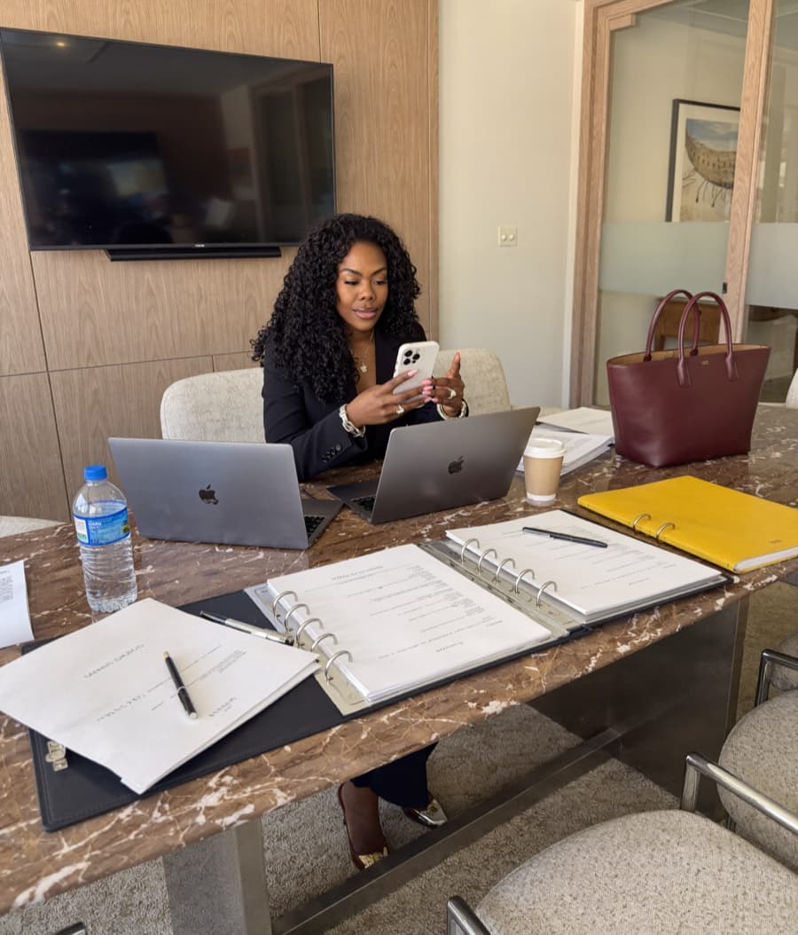 Zuleema working at her desk, laptops open, phone in hand