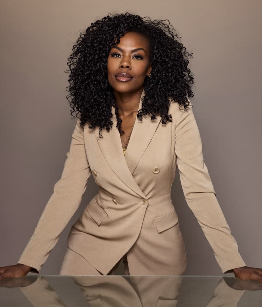 Zuleema leaning on a glass table, direct and thinking it through